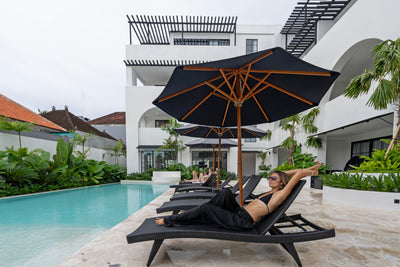 Современный бассейн с шезлонгами и зонтиками, девушка отдыхает на одном из шезлонгов у воды